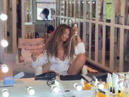 Beyonce in front of a mirror against a white background.