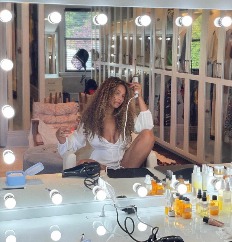 Beyonce in front of a mirror against a white background.